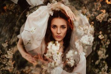 Portrait of a romantic girl in a blooming garden with elements of phantasmagoria. The concept of fantasy, fairy tales. - obrazy, fototapety, plakaty