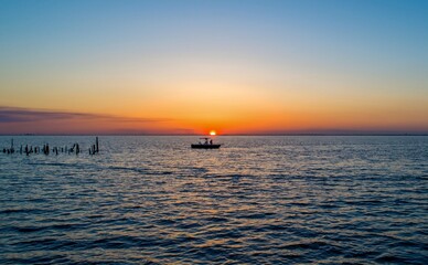 Naklejka na ściany i meble Fishing on the bay at sunset