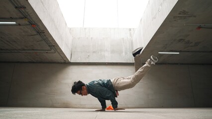 Stylish happy hipster perform break dance or freestyle foot step in building. Professional break...