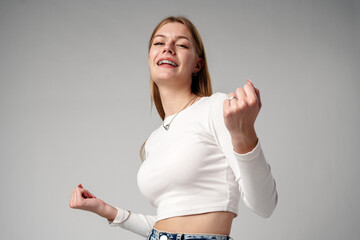 Smiling Young Woman in White Top Celebrating Success With Raised Fist