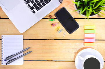 Flat lay design of work desk with laptop notebook, smartphone, pen, sticky note and notepad on wooden background.