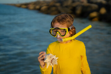 Summer snorkeling with kids. Beach vacation. Fun kid wearing a snorkel scuba mask found coral or shell in ocean water. Summer Kids Snorkeling diving. Child dives into the water. Kids summer holidays. - 786894589