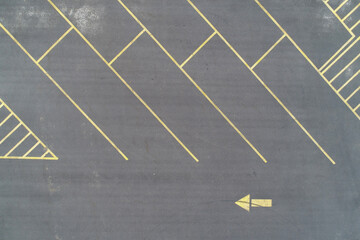 Asphalt parking lot with yellow lines an leftpointing arrow