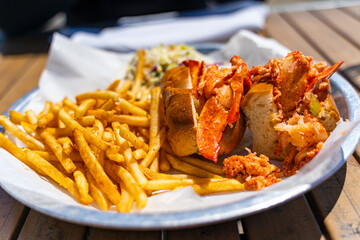 A lobster roll and French fries on a plate in a restaurant.