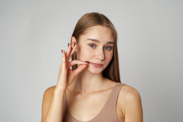 Young Woman Making a Hush Gesture against gray background