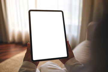 Mockup image of a woman holding digital tablet with blank desktop screen while sitting on a sofa at home - 786899940