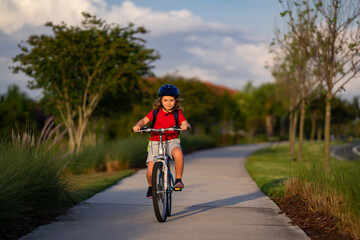 Kid riding bike in a helmet. Child riding bike in protective helmet. Safety kids sports and activity. Happy kid boy riding bike in summer park. Bike helmet, bicycle safety, cycling accessories.