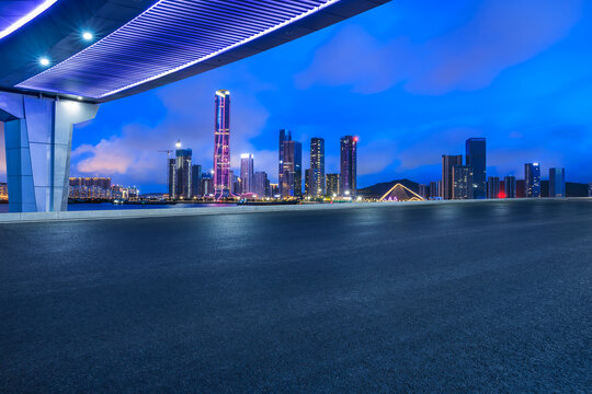 Asphalt road and pedestrian bridge with modern city buildings at night in Zhuhai