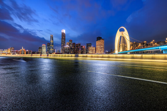 Asphalt road with modern city buildings scenery at night in Guangzhou. Road and city buildings after rain.