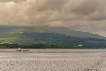 Petit phare blanc et rouge au milieu de détroit au large de l'île de Mull avec vue sur les montagnes © Joachim Beauvilain