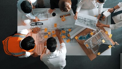 Top down view of skilled engineer team talking while looking at project plan. Aerial view of group...