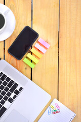 Flat lay design of work desk with laptop notebook, smartphone, pen, sticky note and notepad on wooden background.