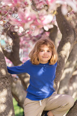 Adorable kid in spring garden. Happy childhood. Kids face near spring park. Kid Happiness. Childrens day. Cute little child under a blossom tree. Kid spring. Kids portrait in blooming cherry tree. - 786924303