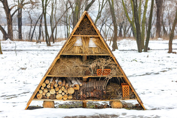 Winter hotel for insects in a park among the snow on the river bank. - 786926106