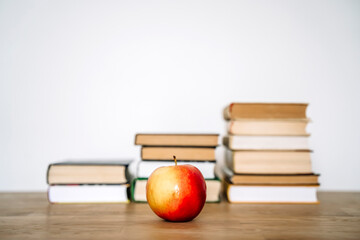 Books and an apple on a desk in a school or university classroom. Education, study concept background