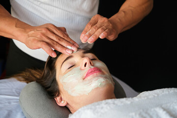 Woman getting an organic facial mask application at spa salon. Facial treatment. Skin care. Health...