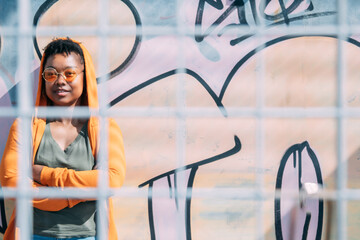 african american woman with arms crossed on graffiti wall