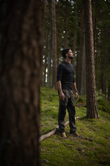 Naklejka na ściany i meble Man standing in nature in the middle of moss and pines.jpg