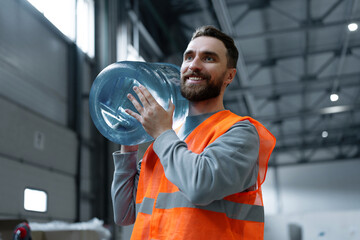 Portrait of smiling, handsome worker, bearded man, courier carrying plastic bottle of water