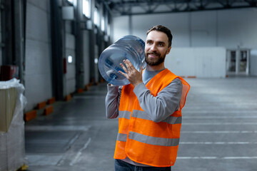 Happy, attractive, bearded man, worker wearing workwear, vest carrying bottle of water, looking away