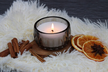 Kerze mit Weihnachtsduft: Aromakerze mit traditionellen Wintergewürzen, Scheiben von Orangen,  und Zimtstangen	