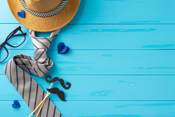 Creative and stylish Father's Day setup featuring a straw hat, elegant necktie, glasses, and playful mustache cutout on a blue wooden background - Powered by Adobe