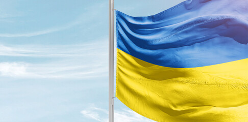 Ukraine national flag with mast at light blue sky.