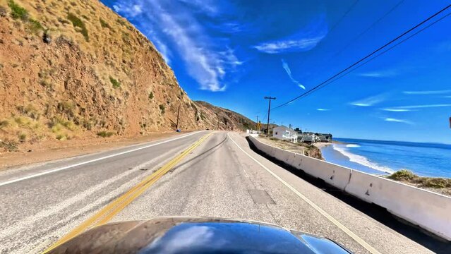 Immersive, establishment point of view of a cruise down the classic Pacific Coast Highway 101 to Malibu, California.  Enjoy scenes of sun, sand and surf below the bright blue skies.