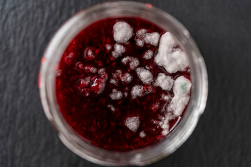 Mold in a glass jar of red raspberry jam, close up, top view. Mold is very dangerous to health - obrazy, fototapety, plakaty