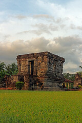 Candi Naga (Dragon Temple) with green grass in the foreground, is an ancient building located in the Penataran Temple complex with dragon relief ornaments wrapped around the temple body.