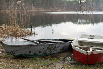 Dwie stare łódki na brzegu malowniczego małego jeziora - obrazy, fototapety, plakaty