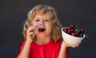 Happy little child with cherry. Kid picking and eating ripe cherries. Child holding fresh fruits. Healthy organic berry cherry fruit. Gray background. Healthy food. - 786952307