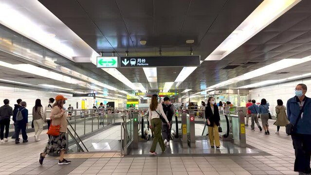 In Taiwan's MRT station, there are crowds of people walking around and the escalators