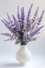A white vase filled with purple flowers. Suitable for home decor or floral arrangements