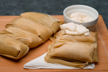 Central American tradition: savory tamales wrapped in corn leaves, served with creamy goodness, a taste of El Salvador
