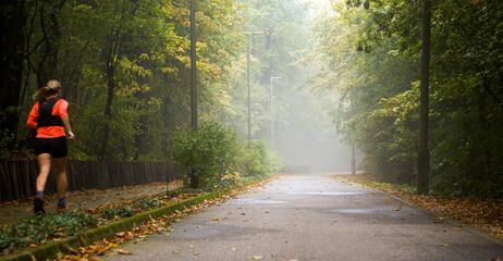 Foggy park lane, woman running 