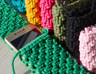 Small handbag for a mobile phone. Knitting macrame, pattern of multi-colored cotton cords. Handmade concept, hobby.