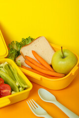 Yellow lunch box with food on a yellow background