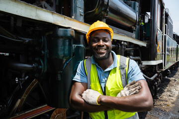 A man in a yellow vest is standing next to a train. He is smiling and posing for a picture