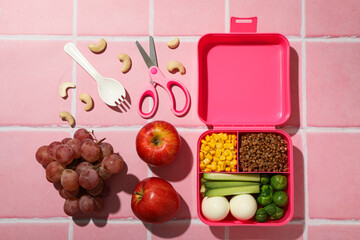 Pink lunch box with food and fresh fruits