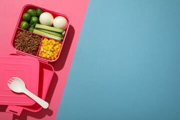 Pink lunch box with tasty food and plastic spoon