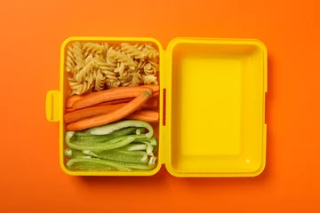 Keuken spatwand met foto Yellow lunch box with food on an orange background © Atlas
