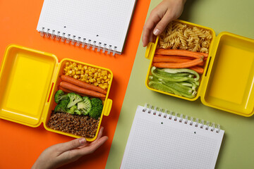 Yellow lunch box with healthy food and notebooks