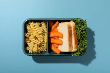 Keuken spatwand met foto Blue lunch box with food on a blue background © Atlas