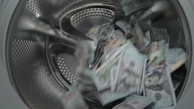 Washing a heap of one hundred dollar bills in washing machine, inside view of drum during spin cycle. Concept of money laundering, financial fraud.