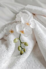 Obraz na płótnie Canvas A white towel adorned with two delicate white flowers. Perfect for spa or beauty concepts