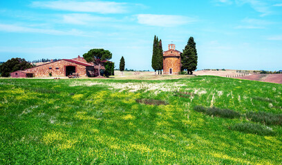Fototapeta premium charming landscape with chapel of Madonna di Vitaleta near rape field on a sunny day in San Quirico d'Orcia (Val d'Orcia) in Tuscany, Italy. Excellent tourist places.