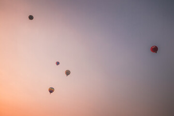 Multiple hot air balloons floating in the sky at sunset