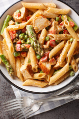 Spicy Chicken Chipotle Pasta with asparagus, bell pepper, green pea and onion closeup in the bowl on the table. Vertical top view from above