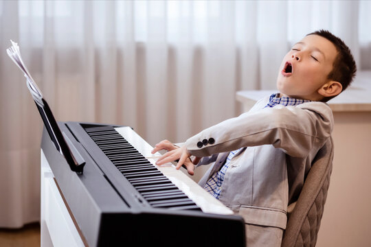 Little Pianist Playing Piano and Singing in Studio. Artistic Happy Musician Boy Singing Vocal with Open Mouth. - Powered by Adobe